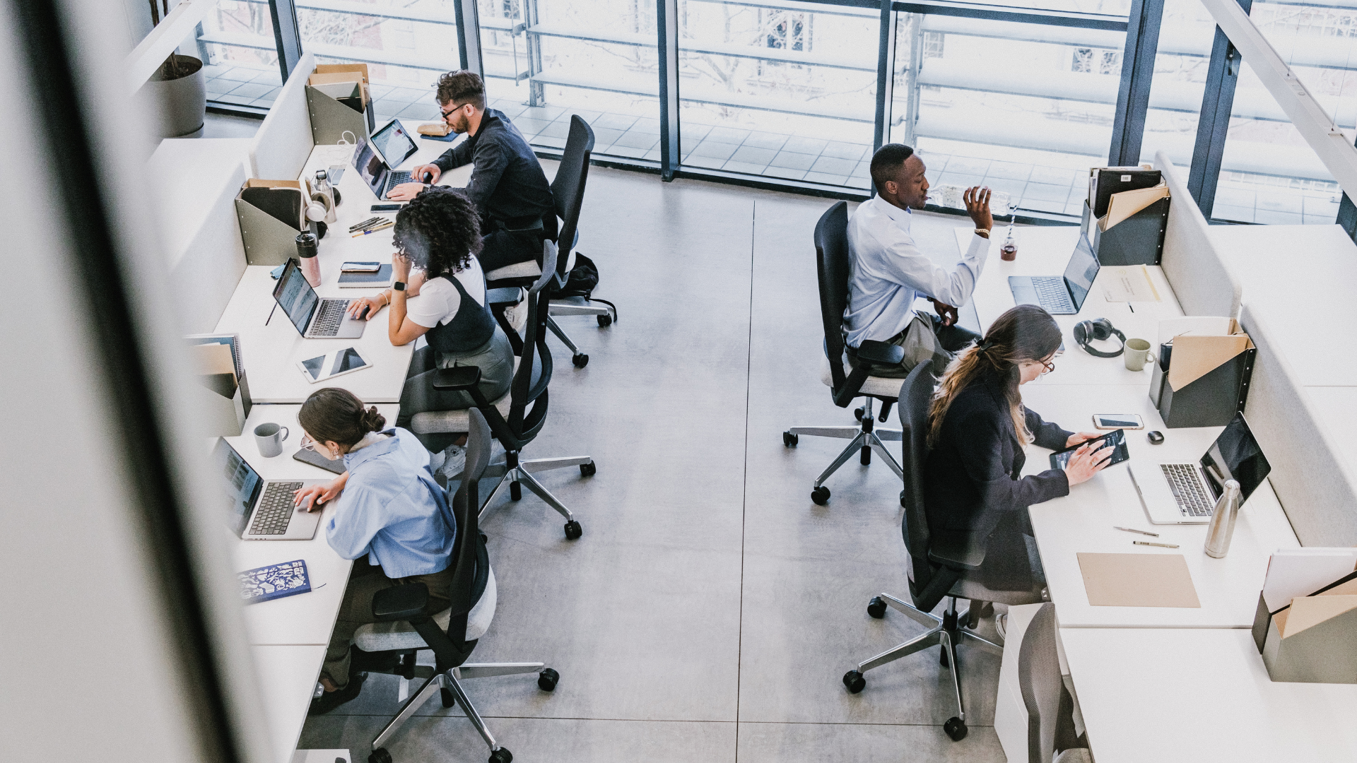 Profissionais trabalham em um escritório corporativo utilizando computadores, notebooks e outros equipamentos de tecnologia B2B.
