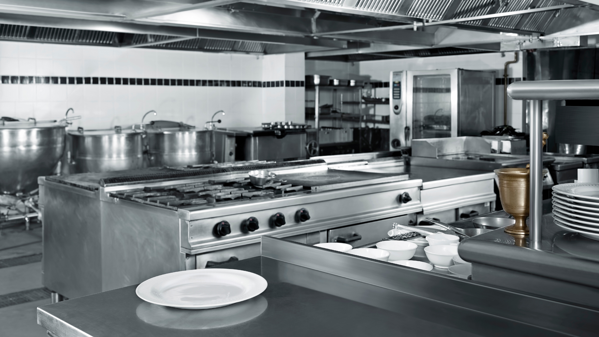 Cozinha industrial equipada com fogões, fornos, bancadas e utensílios de aço inoxidável, representando o ambiente de uso de Mini PC em cozinhas industriais.